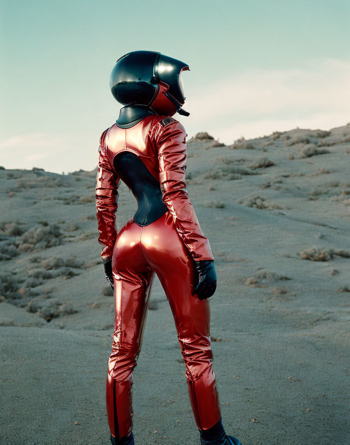 Red shiny spacesuit figure in black helmet in desert landscape