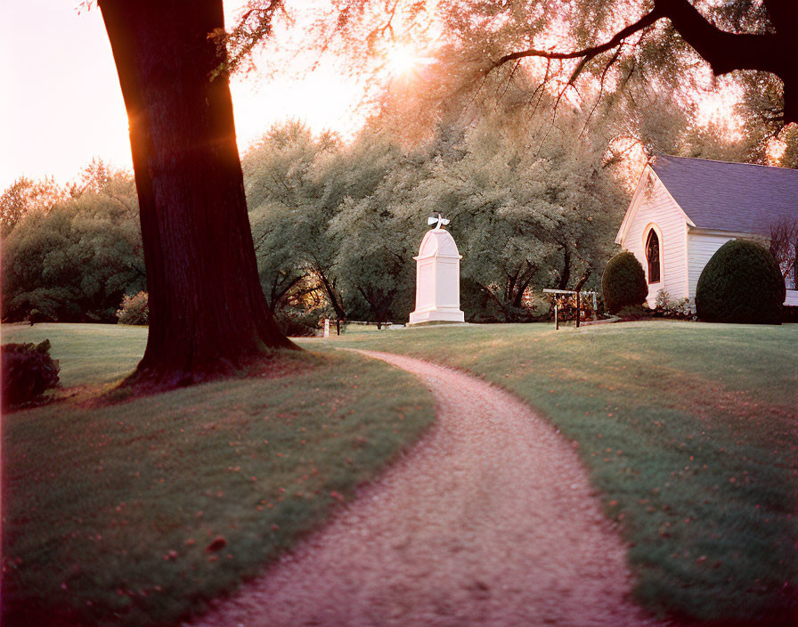 Scenic park path to chapel at sunset among golden trees