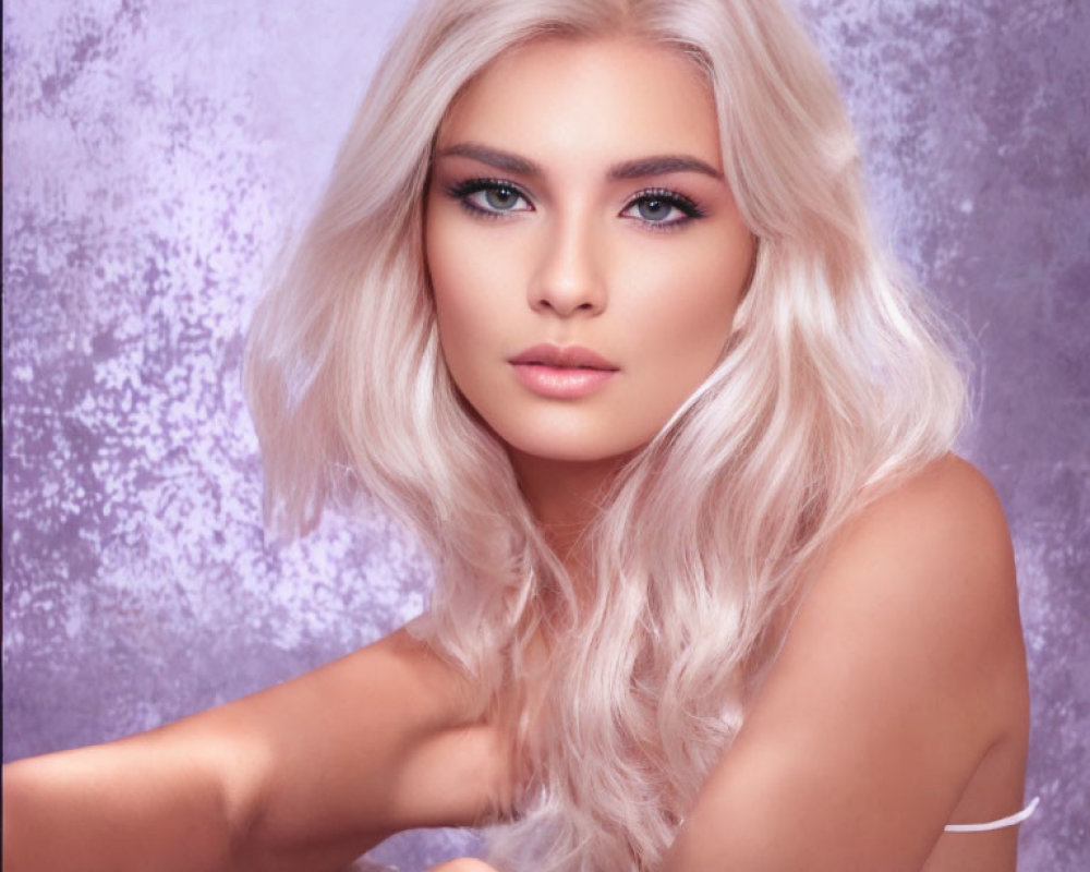 Portrait of a woman with platinum blonde hair and striking makeup on textured backdrop