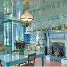 Blue-patterned tiled kitchen with chandelier, fireplace, and green fruit bowl