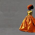 Elegant woman in orange dress against grey background exudes poise