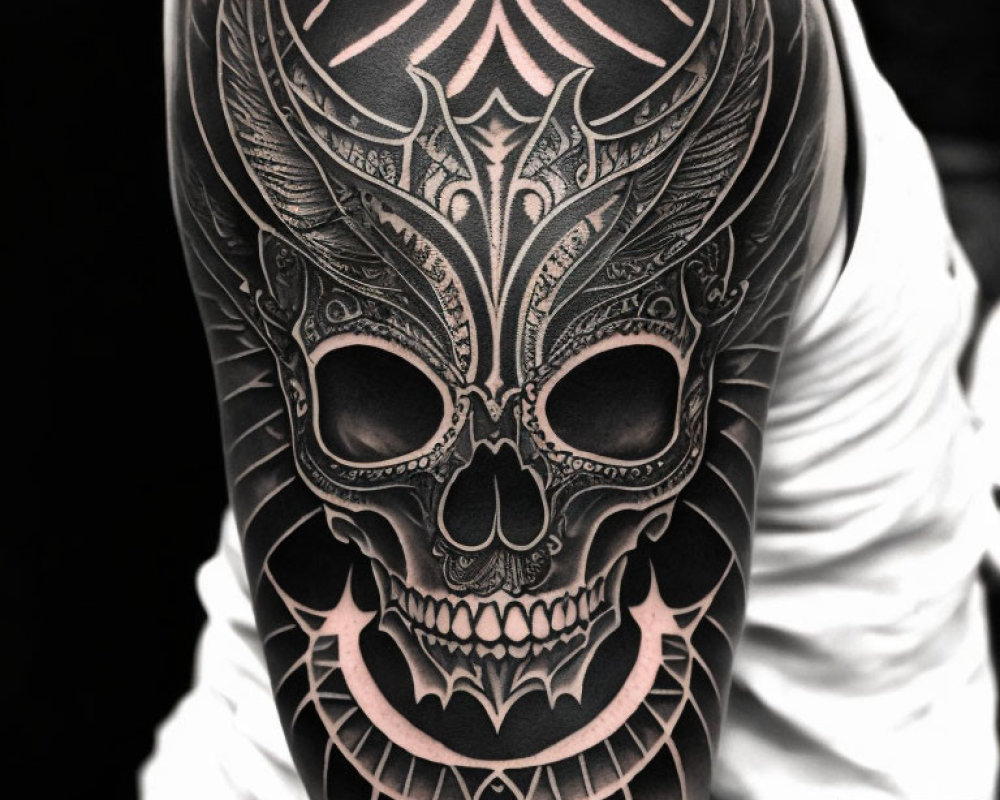 Detailed black and grey ornate skull tattoo on arm with intricate patterns