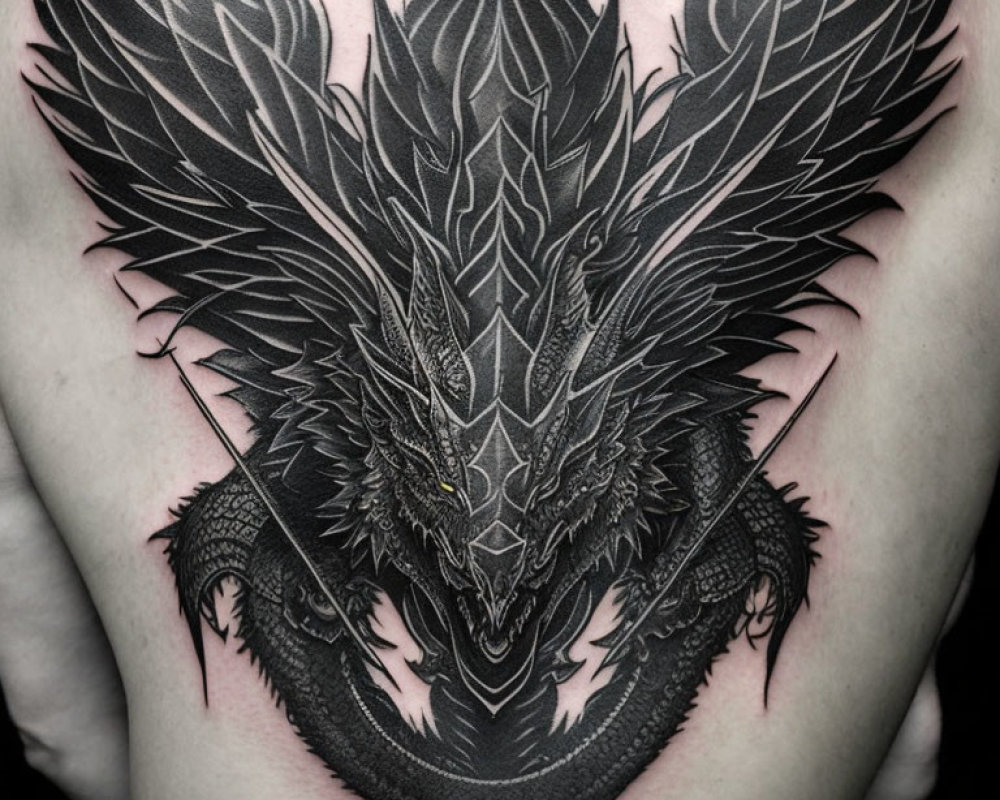 Intricate black ink dragon tattoo on chest with scales and wings.