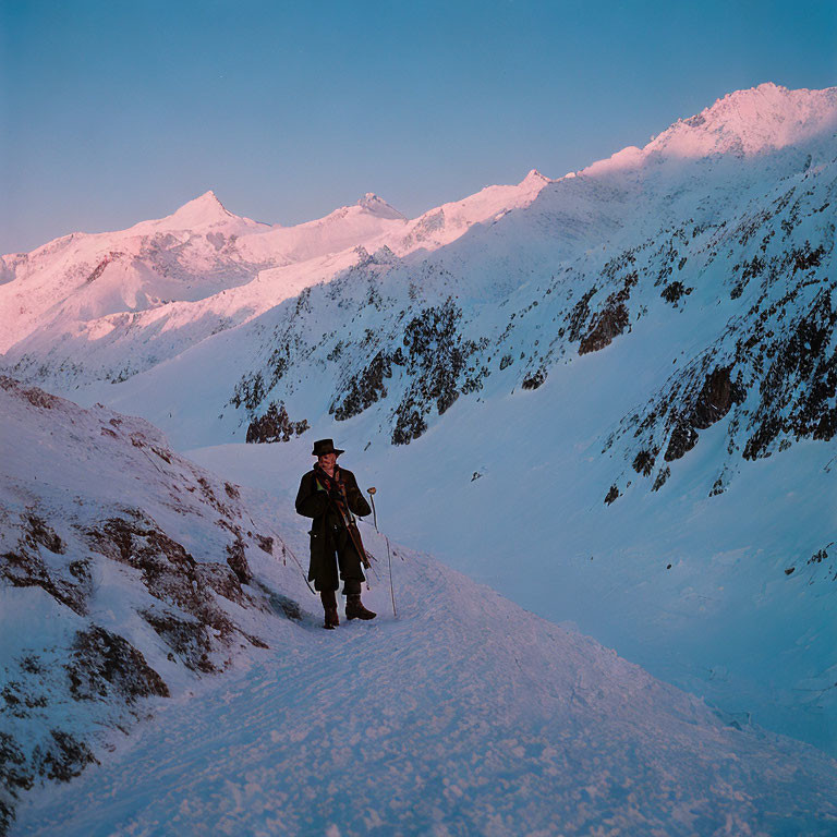 Person in Traditional Attire on Snowy Mountain Path at Dawn or Dusk
