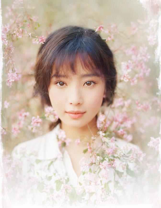 Portrait of young woman with dark hair in soft pink blossoms