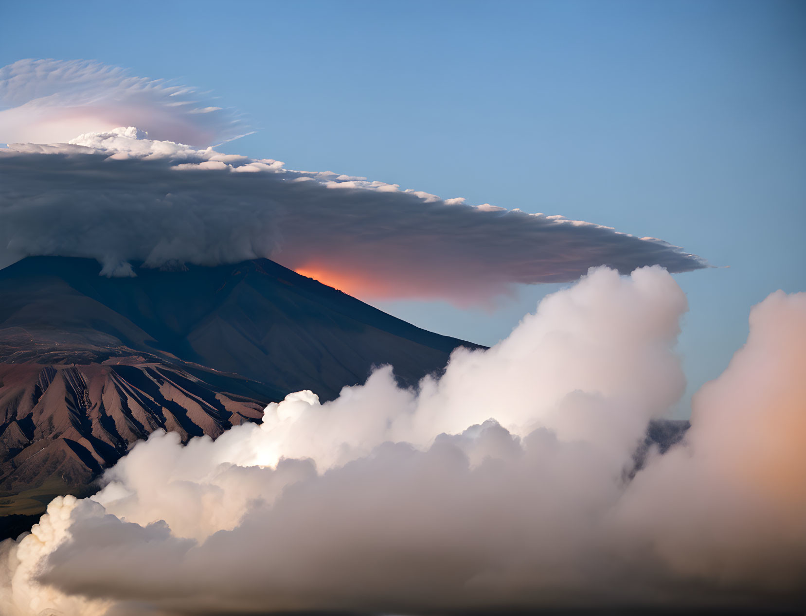 Majestic mountain peak with striking cloud formation at sunset