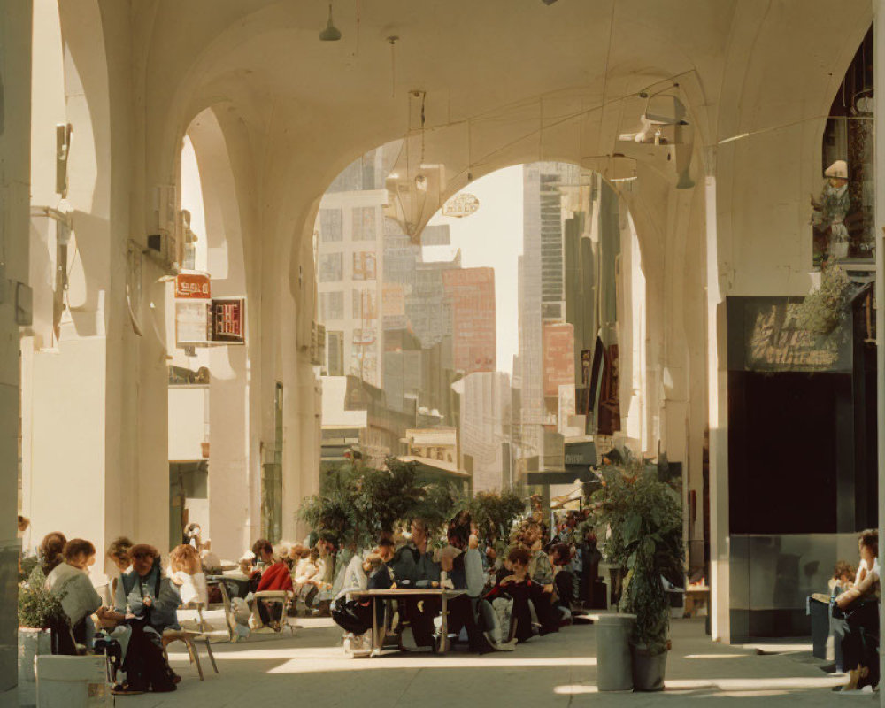 Urban arcade with people at tables, architectural arches, cityscape in background