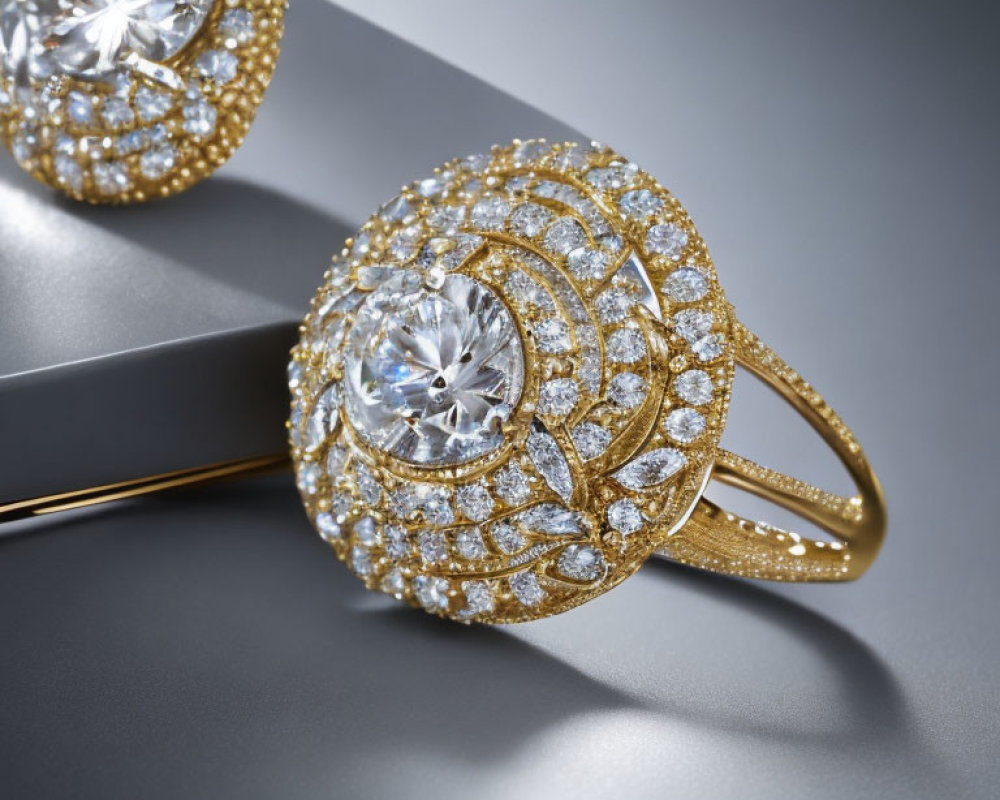 Luxury gold rings with intricate designs and embedded diamonds on reflective grey surface