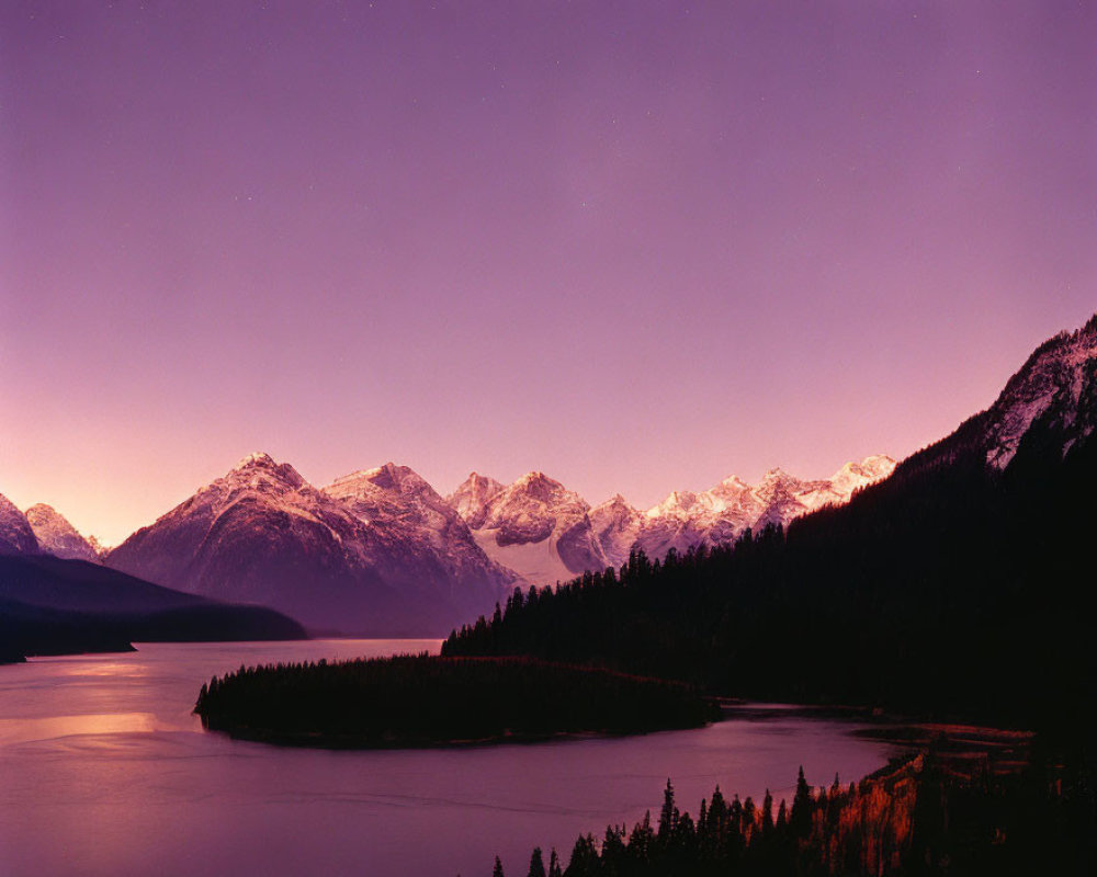 Snow-capped mountains, forest, lake in twilight with purple sky