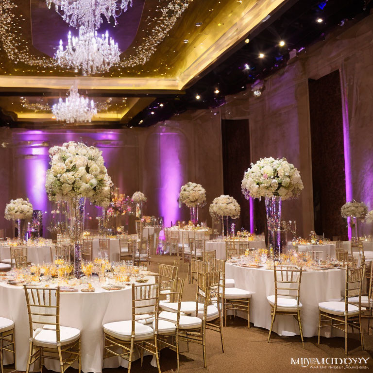 Luxurious Event Decor: Tall Floral Centerpieces, Crystal Chandeliers, Golden Chairs, Purple Lighting