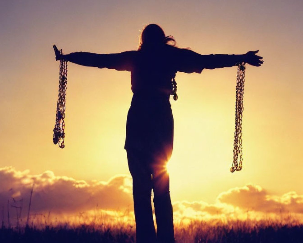 Person silhouette holding chains against sunset sky