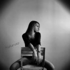 Monochrome portrait of contemplative woman in chair against textured backdrop