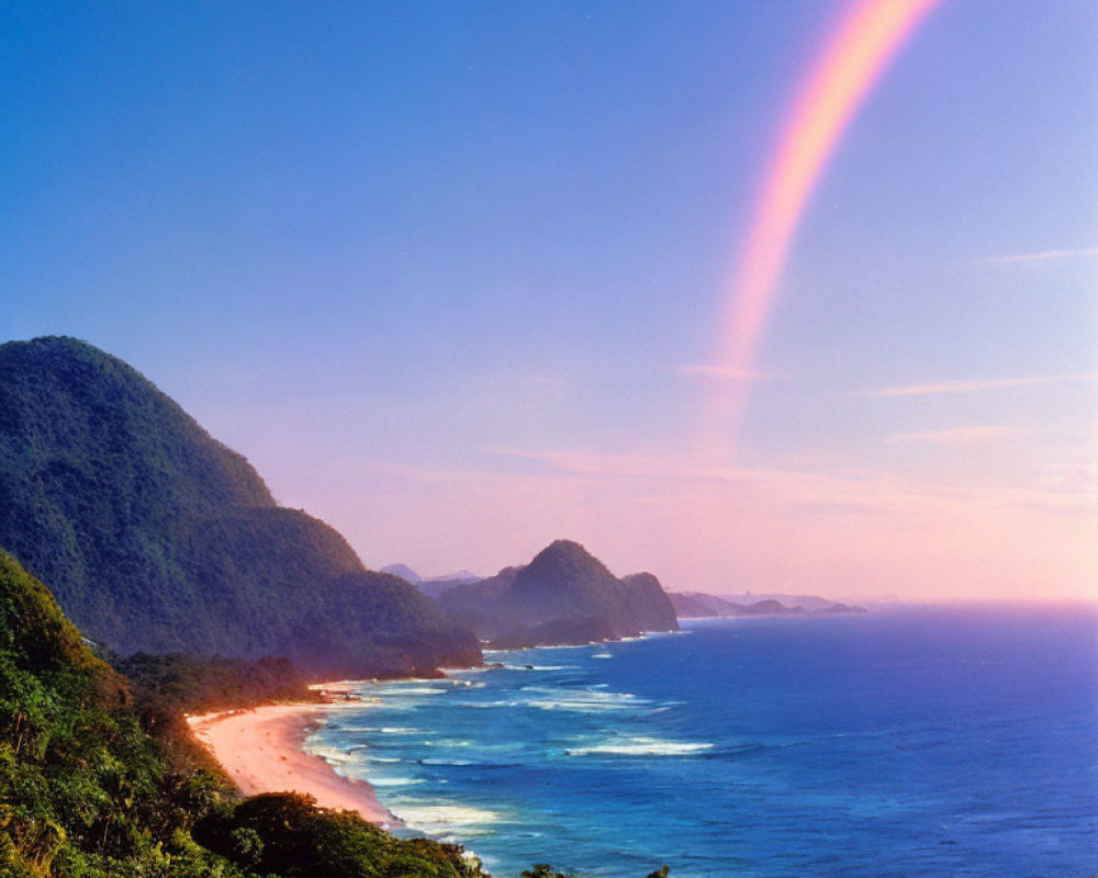 Scenic coastal landscape with rainbow over lush hills