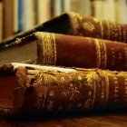 Stack of Ornate Antique Books on Wooden Surface with Blurred Bookshelves