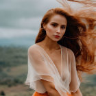 Woman with flowing hair in pale top and orange skirt in windy landscape.