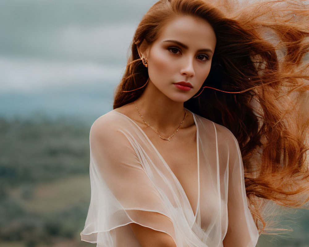 Auburn-haired woman in sheer blouse and orange skirt against cloudy landscape