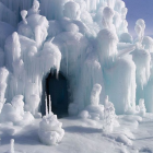 Surreal winter landscape with white tree-like structures and icy cave entrance