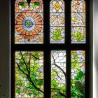 Vibrant floral stained glass window with green foliage on white wall