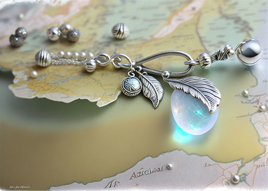 Luminous blue globe charm bracelet with silver leaves and beads on a map