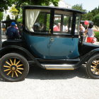 Vintage black and teal car with flowers displayed at outdoor event