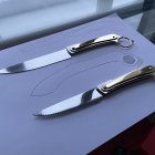 Decorative Folding Knives with Black and Silver Handles on Dark Surface