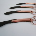 Black-bladed knives with copper accents on light background