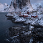 Picturesque Coastal Village with Red Houses and Snowy Mountains at Twilight