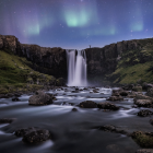 Tranquil night landscape with waterfall, river, forest, and aurora borealis