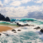 Ocean waves crashing on sandy beach with scattered rocks under cloudy sky