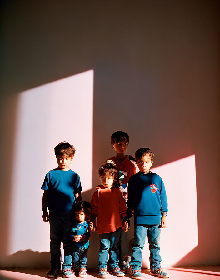 Children standing in a row under natural light with geometric shadows.