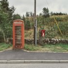 Traditional Red British Phone Booth and Post Box on Peaceful Tree-Lined Street