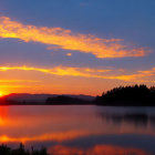 Vibrant sunrise reflections on calm lake and treelined horizon
