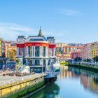 European City Riverside View with Modern Glass Structure & Traditional Buildings