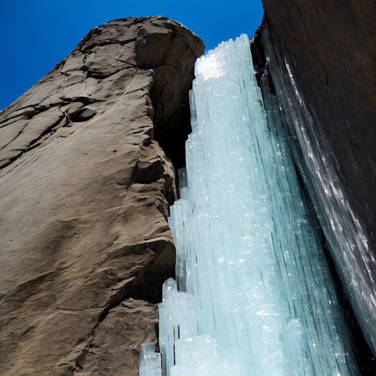 Rocky Cliff with Blue Ice Crystals Against Clear Blue Sky