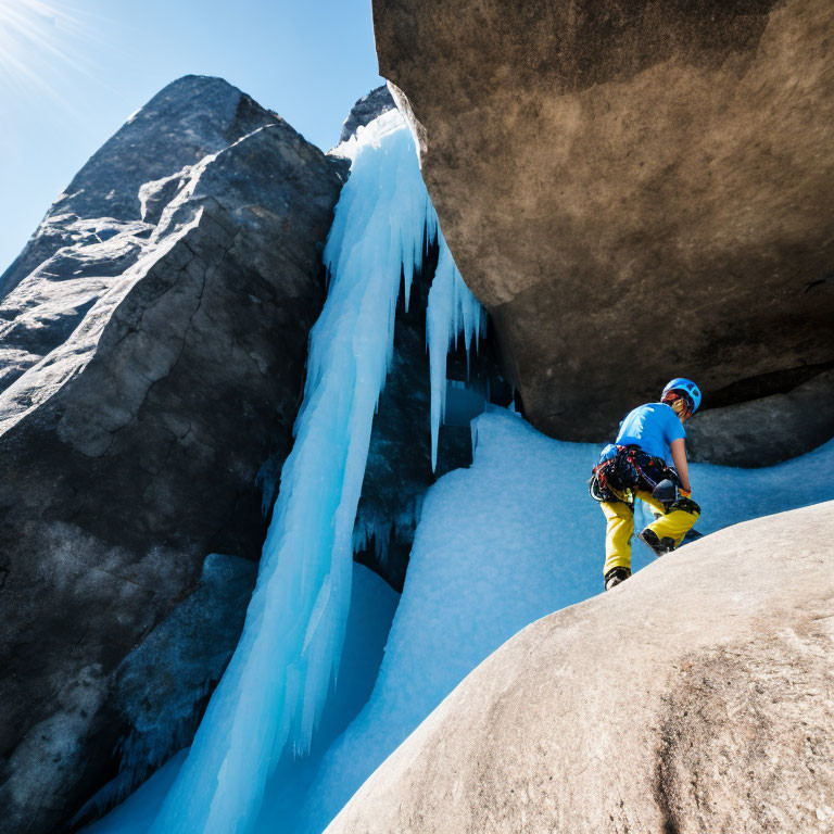 Climber in Blue Helmet Ascending Rocky Slope by Frozen Waterfall