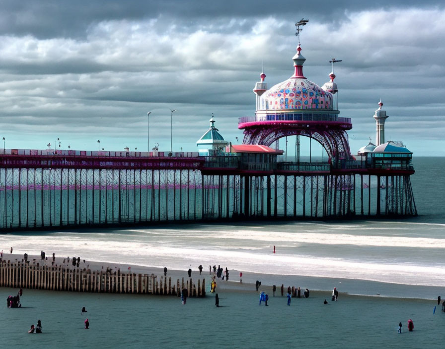 Victorian-style pier over sea with ornate structures and beach-goers below