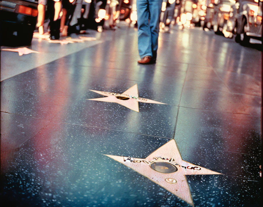 Close-up View of Two Stars on Hollywood Walk of Fame with Blurry Person and Vehicles