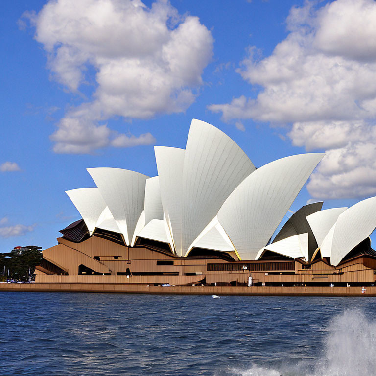 Iconic Sydney Opera House with sail-like design against blue sky.