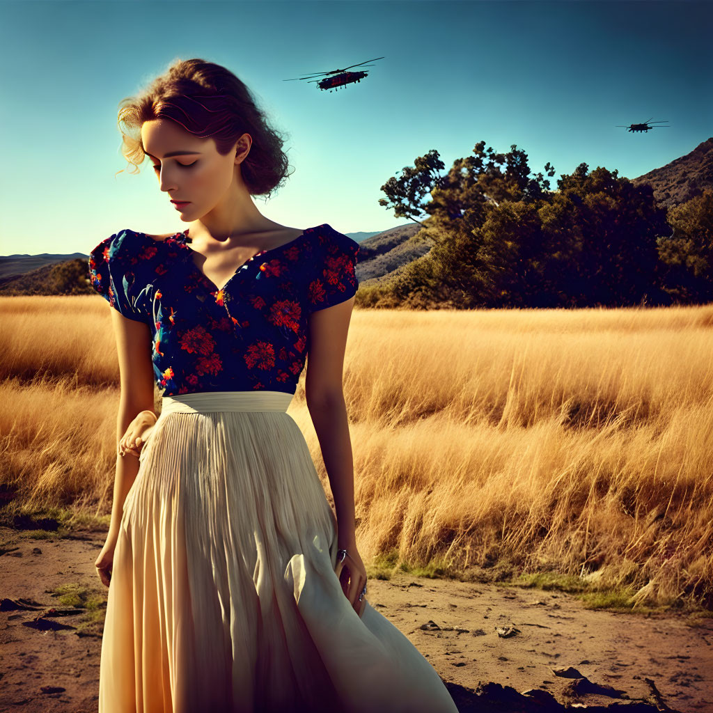 Woman in floral top and cream skirt in golden field with helicopters and clear sky