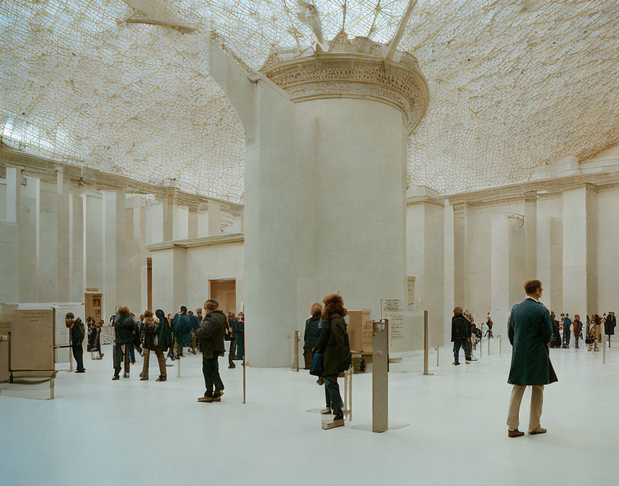 Art gallery with large columns and intricate ceiling installation, visitors observing exhibits