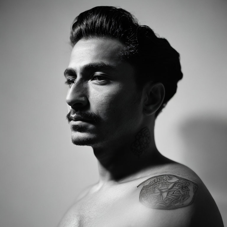 Monochrome portrait of a man with mustache and shoulder tattoo