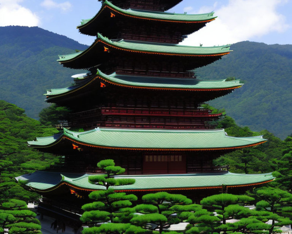 Traditional Japanese Pagoda Surrounded by Green Trees and Mountains