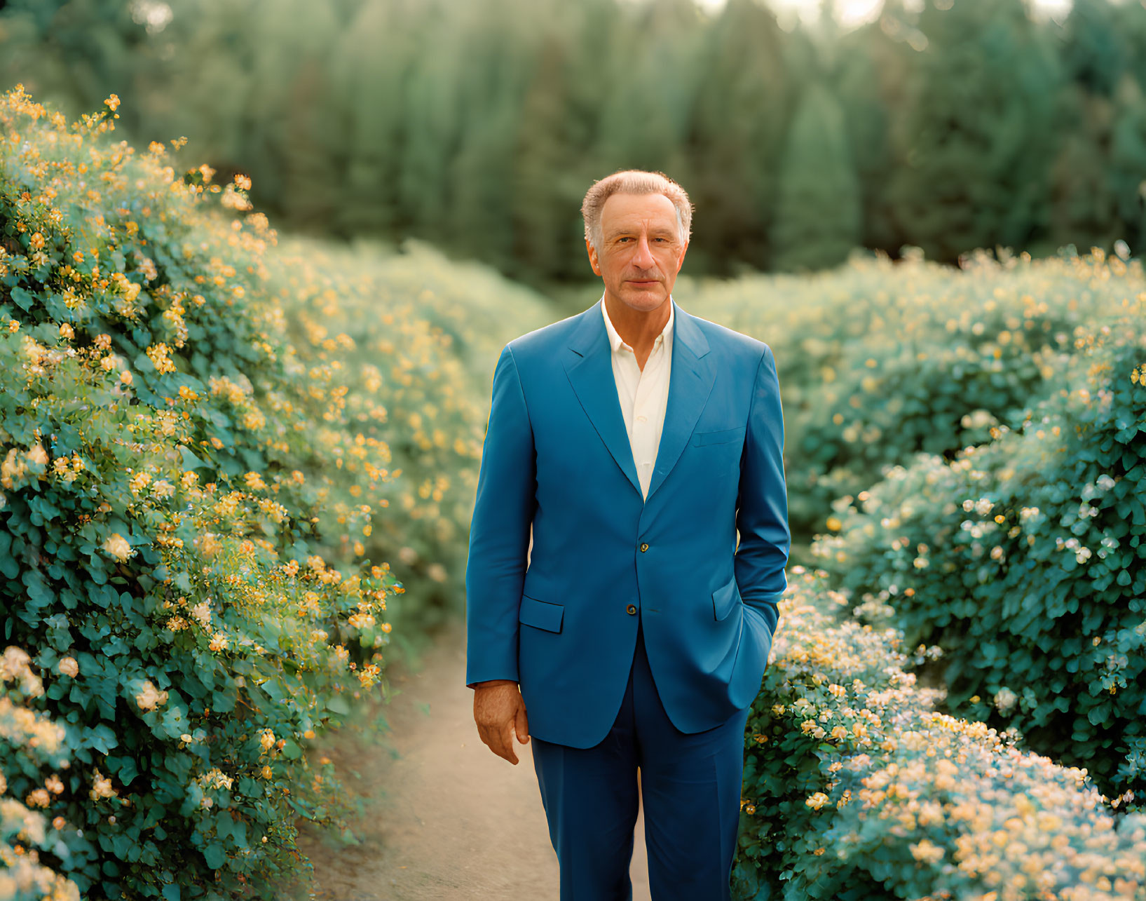 Man in Blue Suit Standing Confidently Among Green Shrubs