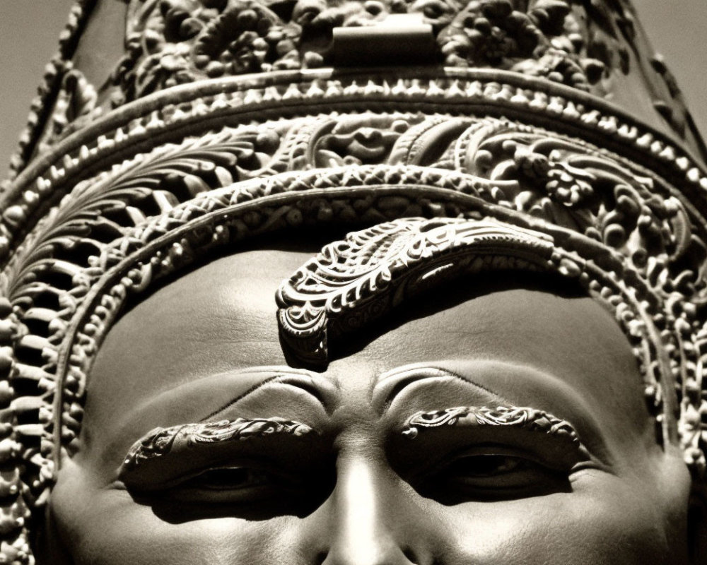 Detailed monochrome statue upper face with ornate crown and forehead decoration.