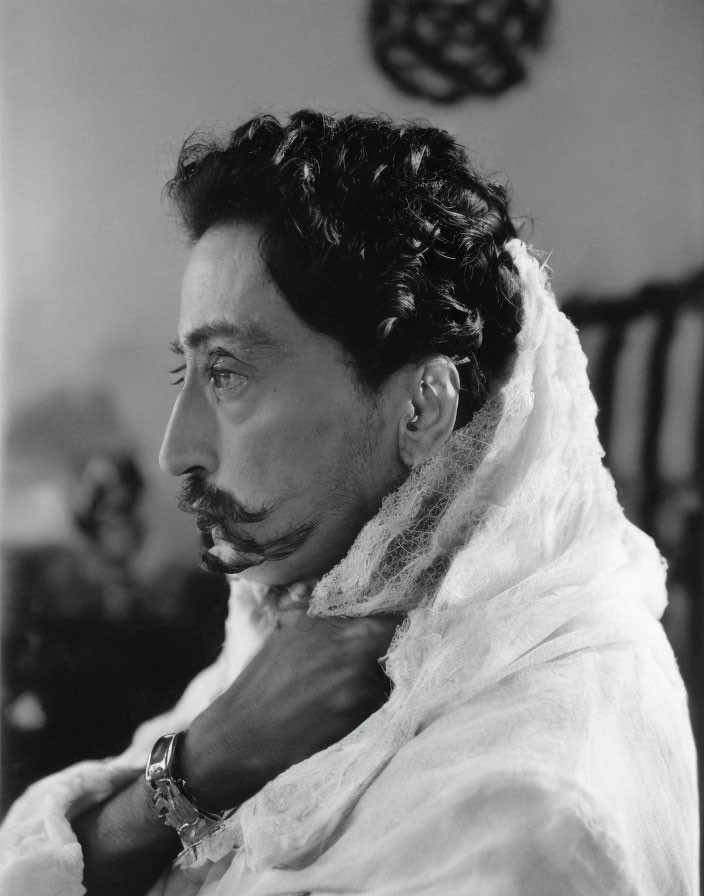 Monochrome profile portrait of a man with curly hair and thin mustache