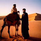 Men in traditional attire with camel in desert at sunset