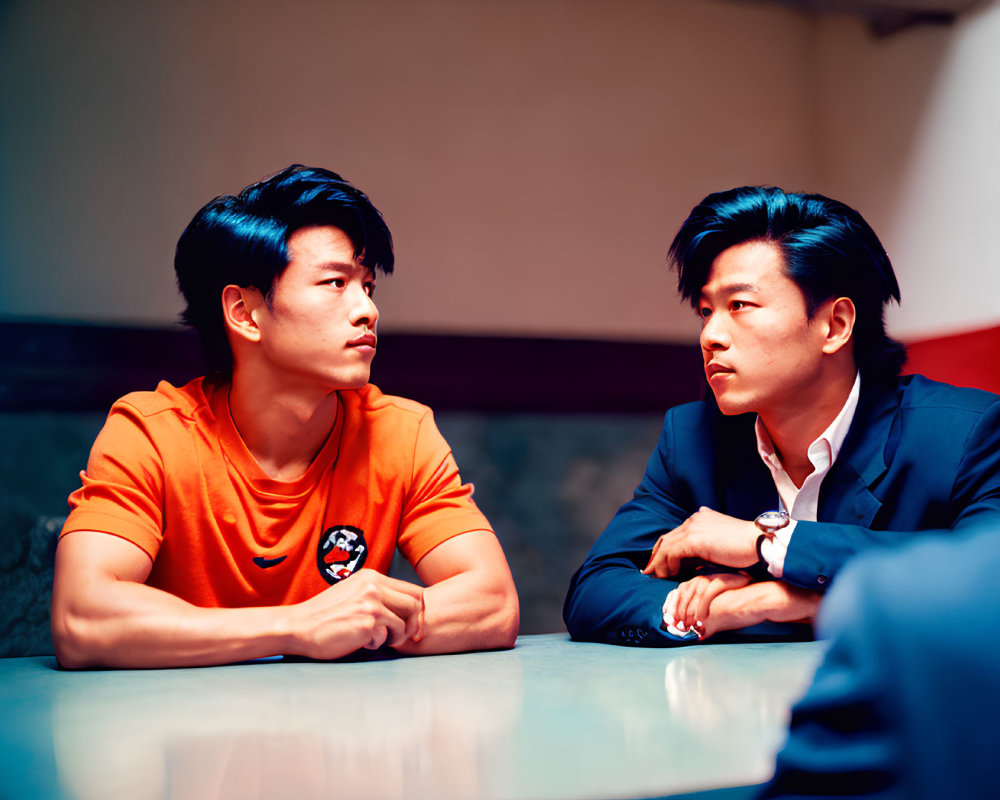 Men in Orange Shirt and Business Suit Engaged in Serious Conversation