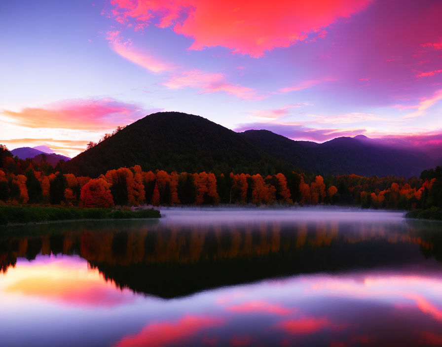 Scenic sunrise: pink and blue skies, autumn trees, mountains, calm lake