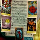 Ornate tarot cards on musical score with cosmic background