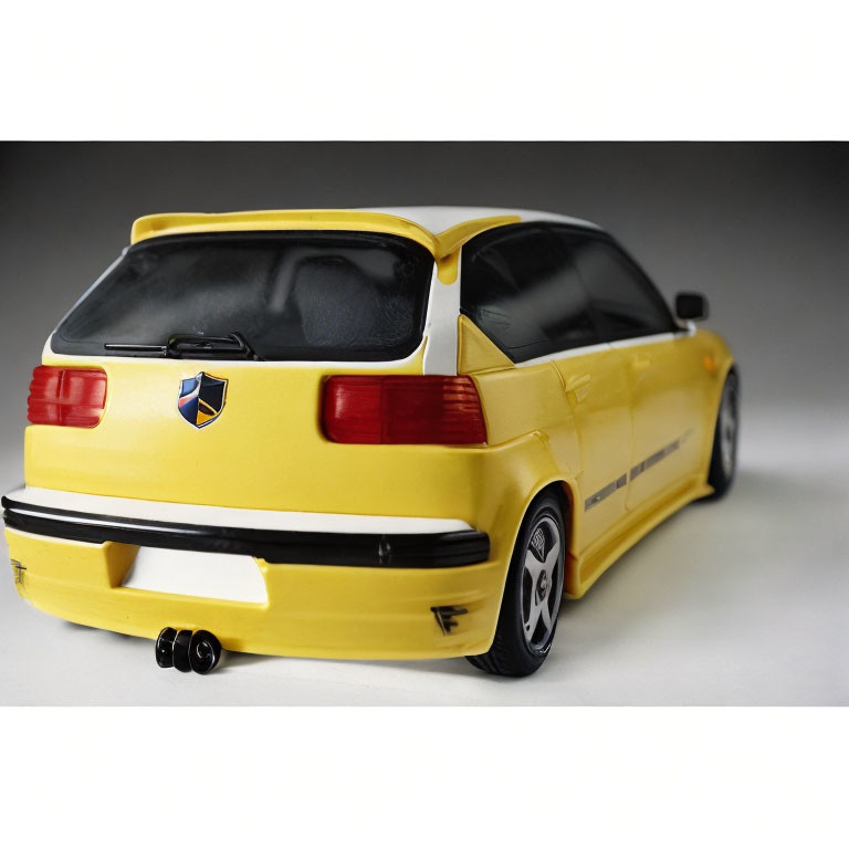 Yellow Toy Sporty Hatchback Car Model with Graphics and Dual Exhaust on White Background